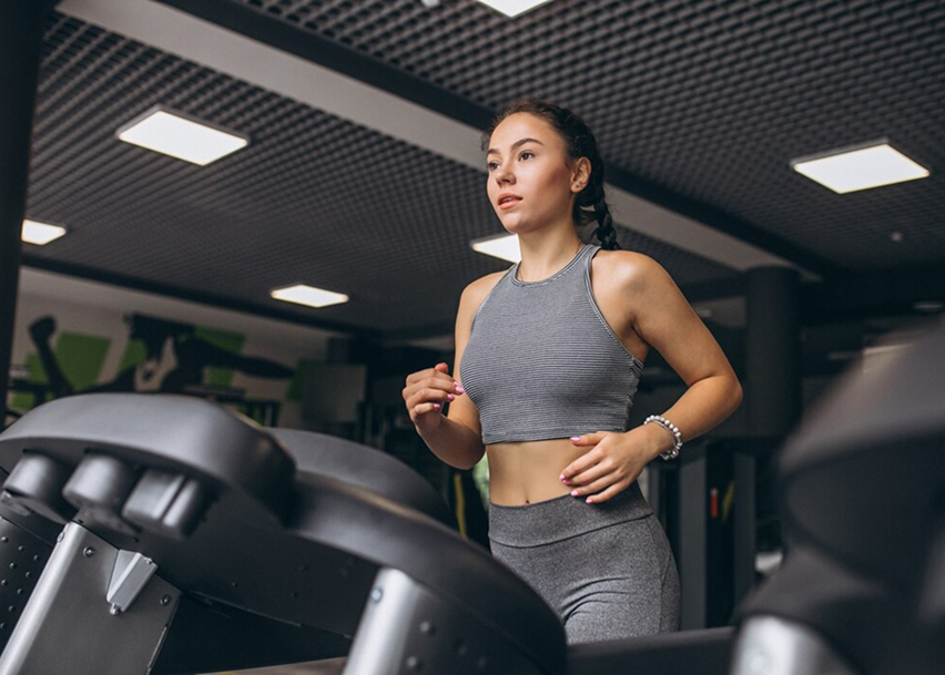 Девушка занимается на беговой дорожке
